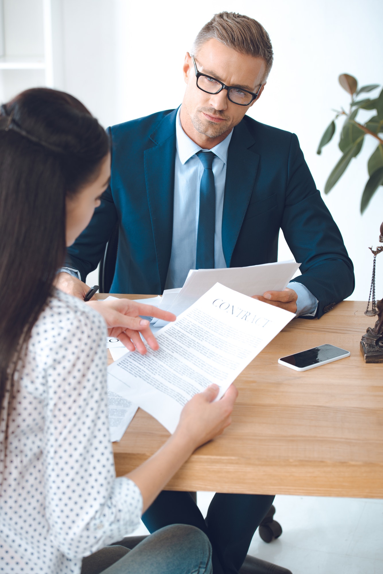 male-lawyer-looking-at-client-reading-contract.jpg